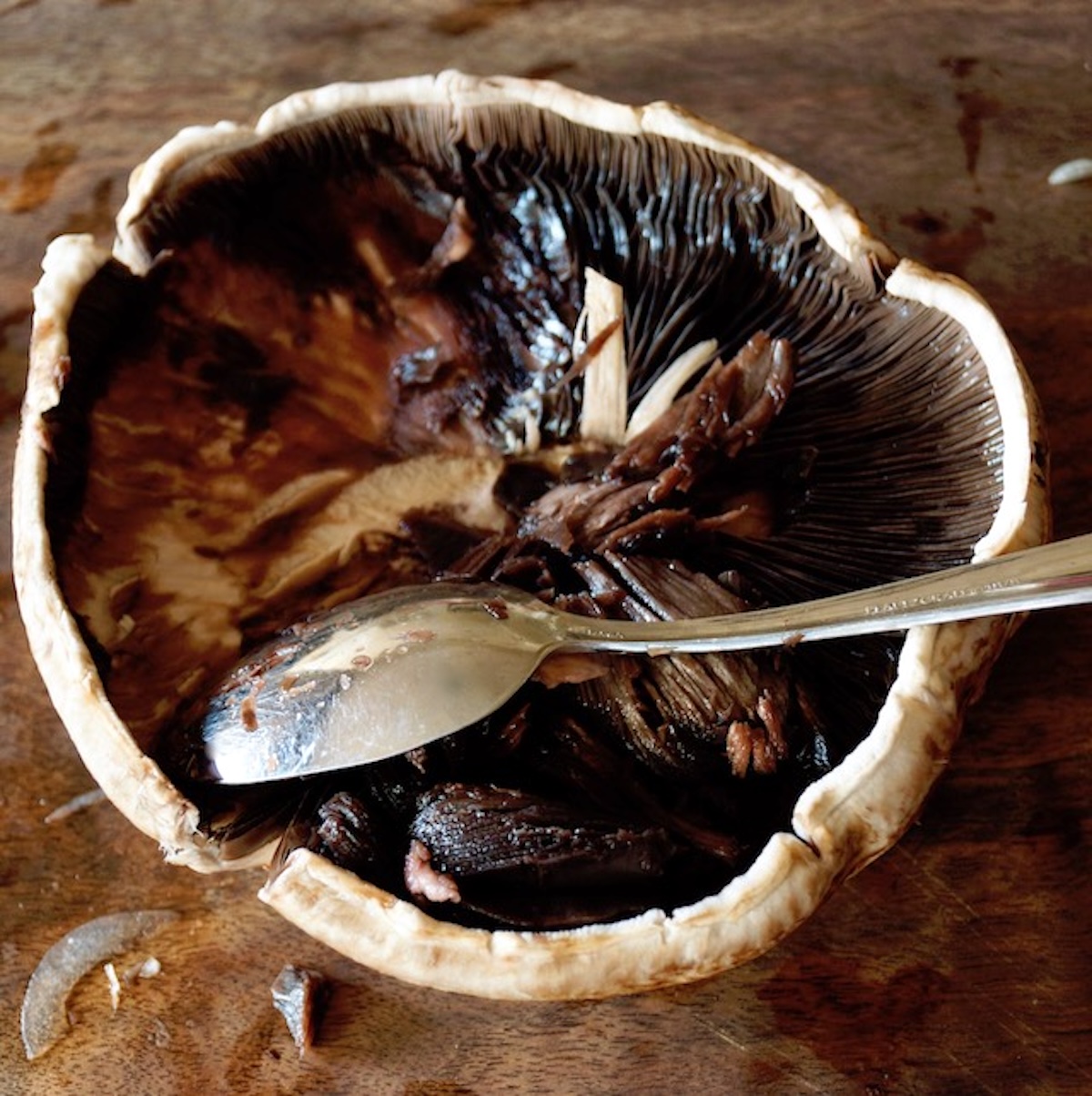 Marinated-Grilled-Portobello-Mushrooms One portobello mushrooms with a small spoon removing the gills.