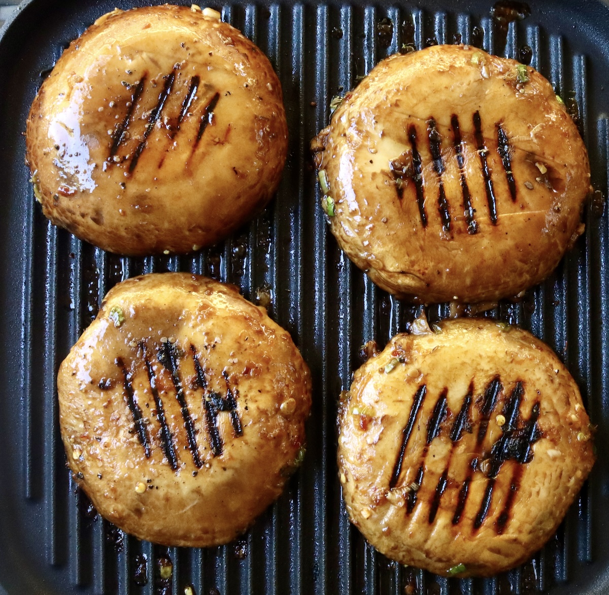 Marinated-Grilled-Portobello-Mushrooms 4 portobello mushrooms, round side up with grill marks, on a grill.
