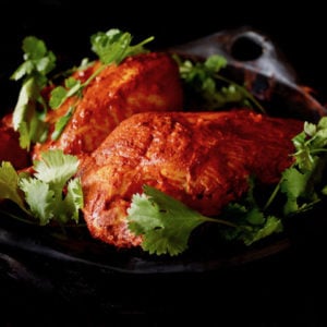 Achiote Chicken in black dish with cilantro