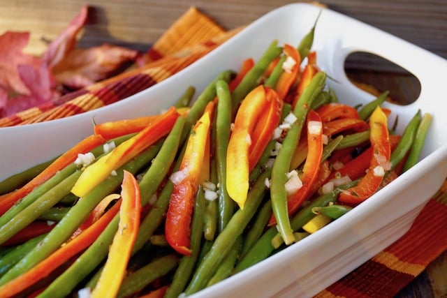 White rectangular serving dish wtih strips of red-yellow Enjoya pepper and green beans.