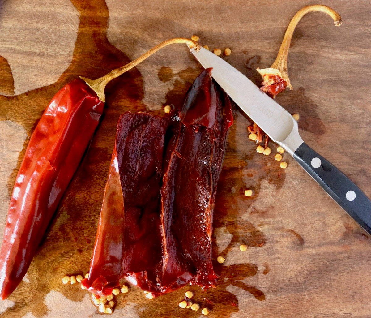 Hydrated Guajillo peppers with a paring knife -- one with seeds removed.