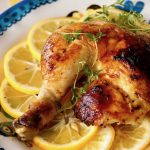 Roasted chicken thigh-leg on lemon slices with fresh thyme.