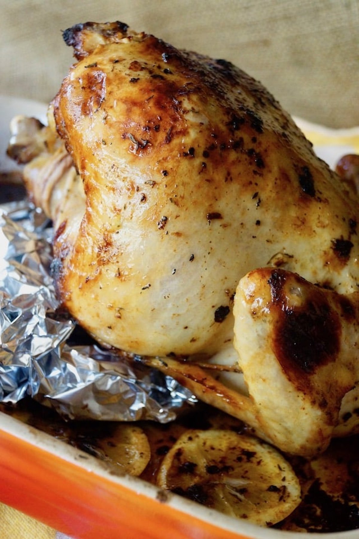 Simple-Lemon-Roasted-Chicken Whole roasted chicken on foil in roasted pan.