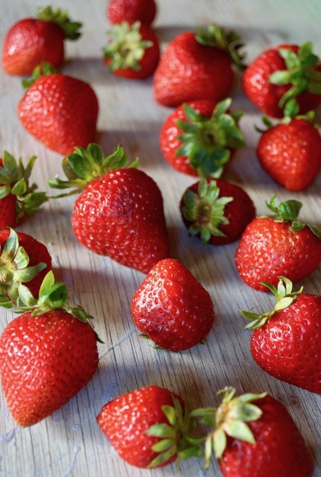 Whole, fresh strawberries on wood table.