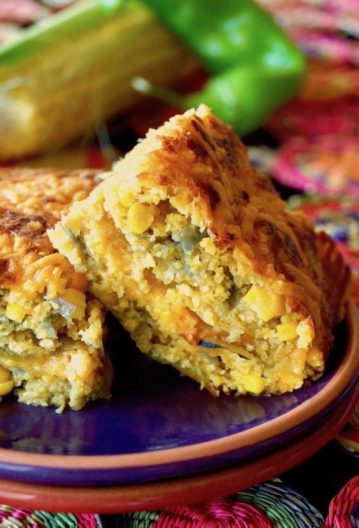 Two square pieces of Hatch chile cornbread on a purple plate with steam coming from them.