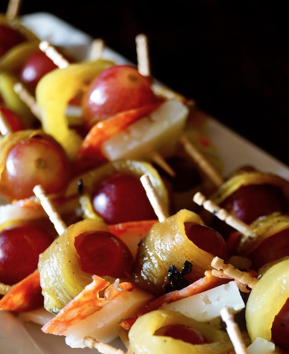 A few grape and roasted hatch chile appetizers on toothpicks.,