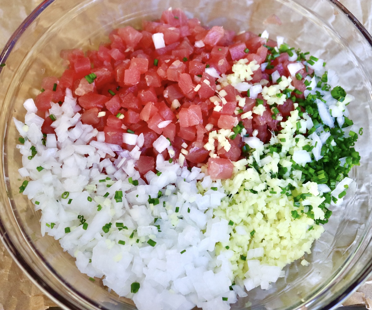 Ahi-Tuna-Tartare-with-Ginger Finely chopped ingredients in a glass bowl for ahi tuna tartare including ahi tuna, white onion, ginger, and chives.