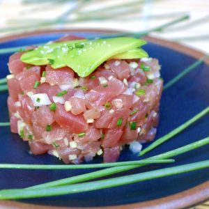 Round mound of tuna tartare with bits of ginger and onion.