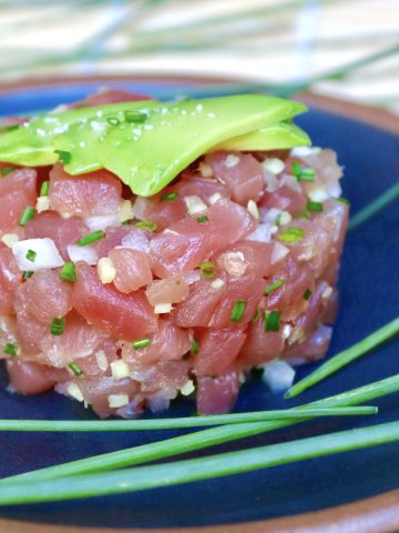 Round mound of tuna tartare with bits of ginger and onion.