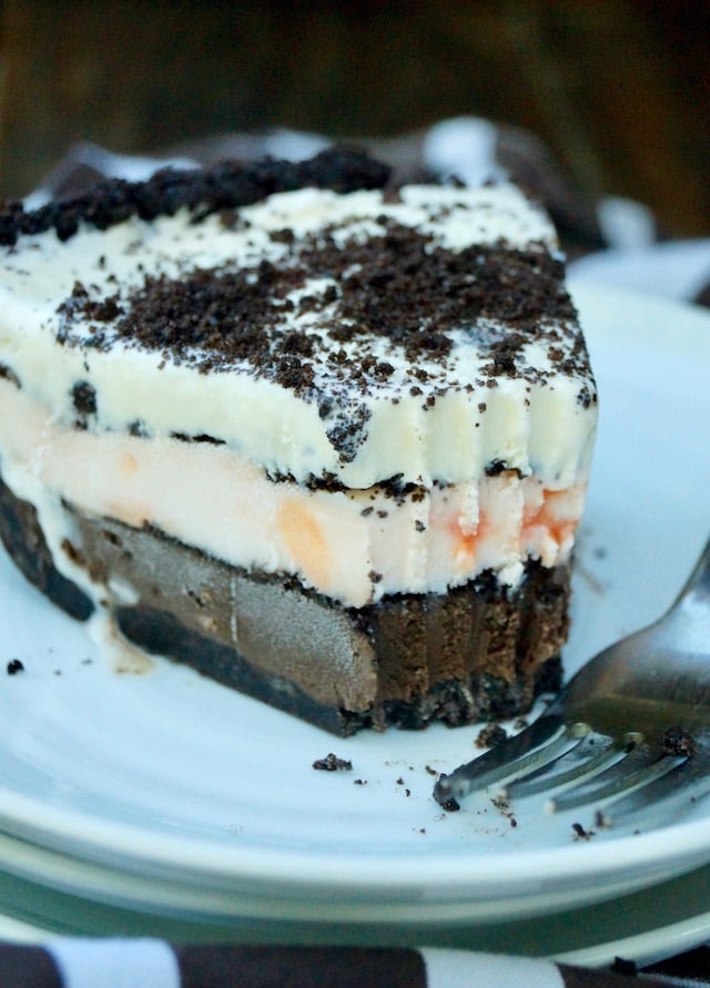 One slice of tri-colored, Chocolate Peppermint Vanilla mud pie on a white plate.