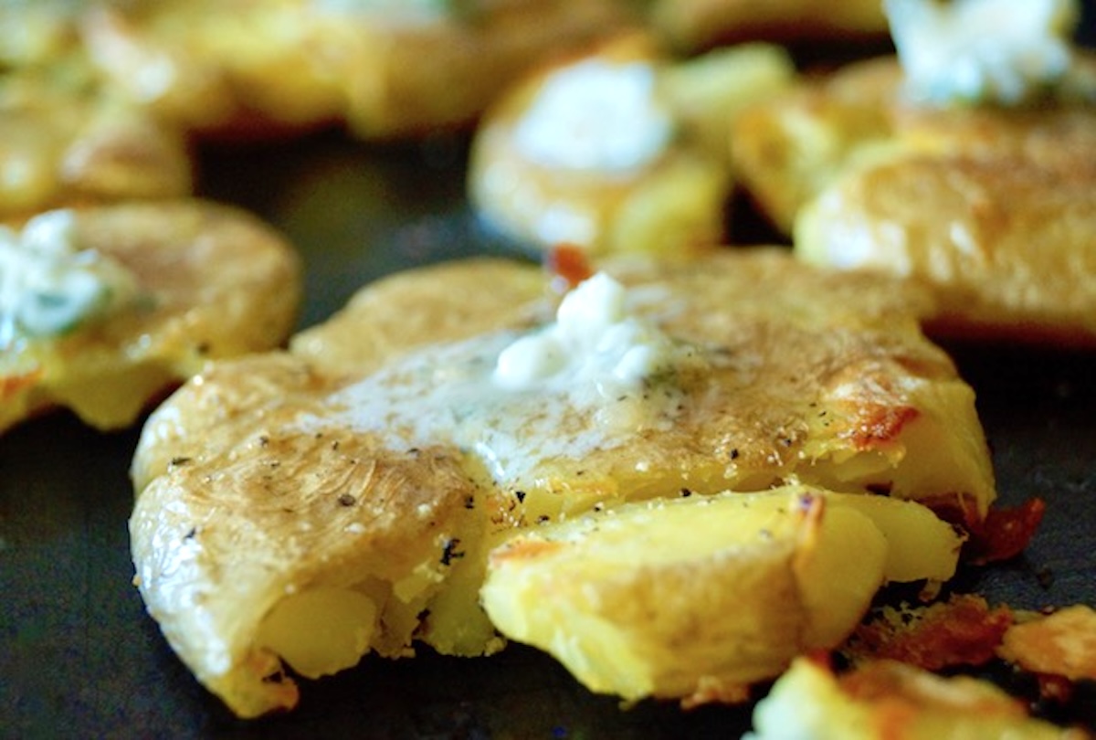 Smashed potatoes with dollops of herb butter on top.