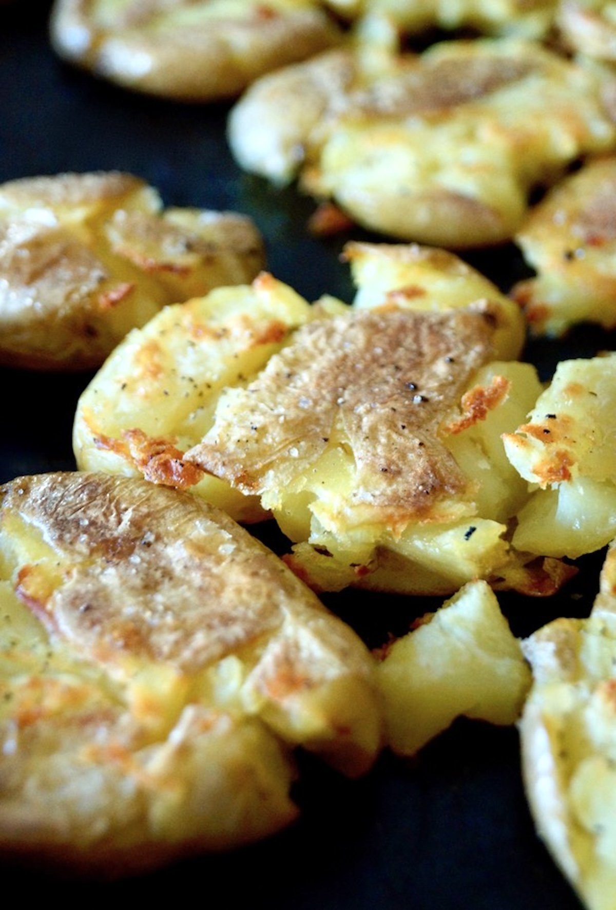 Crispy golden smashed tiny potatoes on a baking sheet.