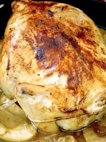 Apple roasted chicken in a cast iron skillet.