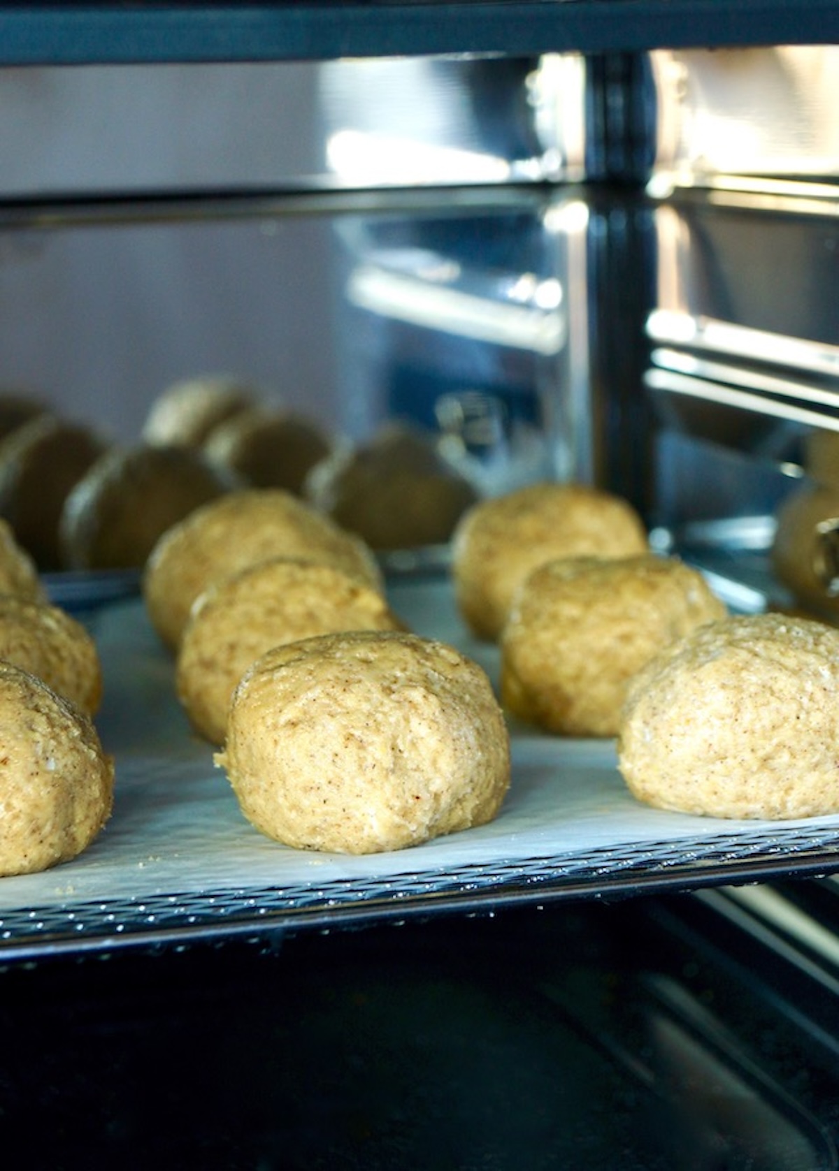 Close up of air fryer with open door with raw pumpkin donut holes on the trays.