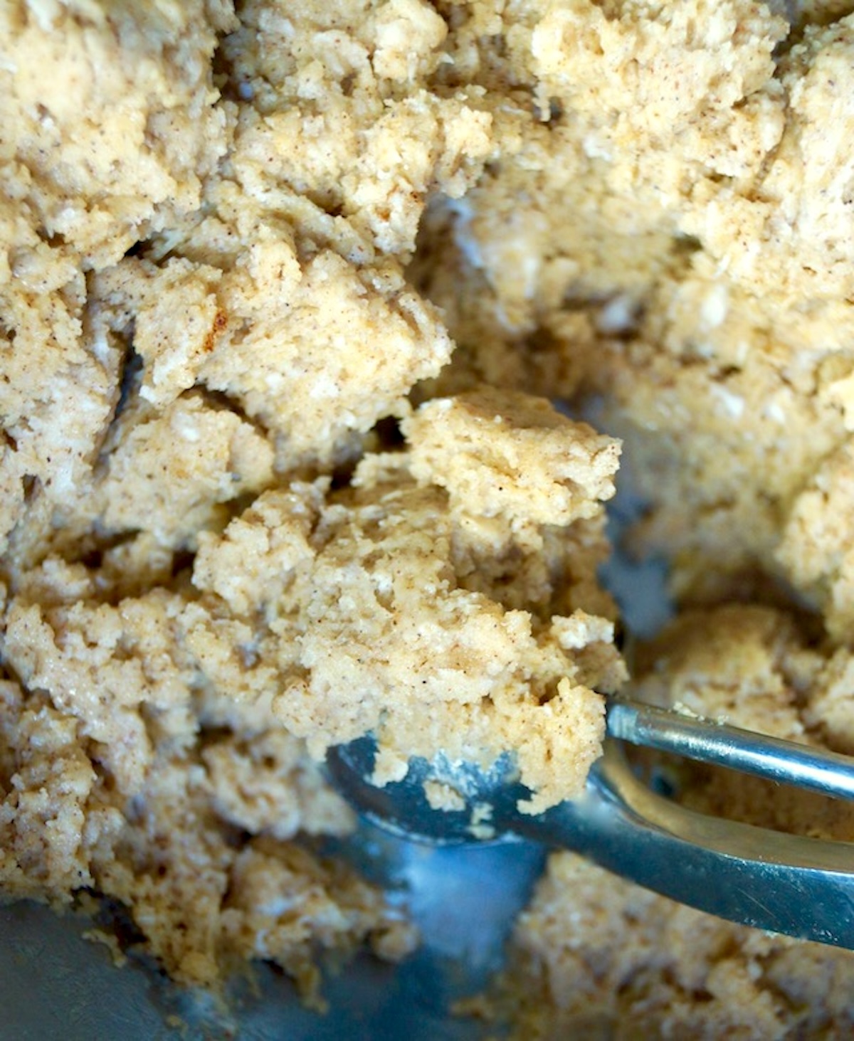 Pumpkin donut batter in a bowl with a cookie scoop.