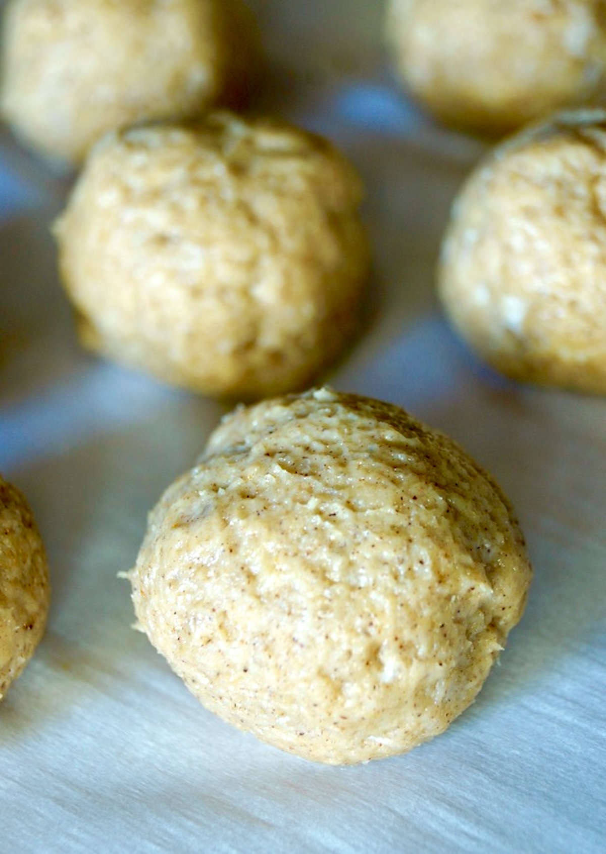 Raw donut holes on a parchment lined baking sheet.