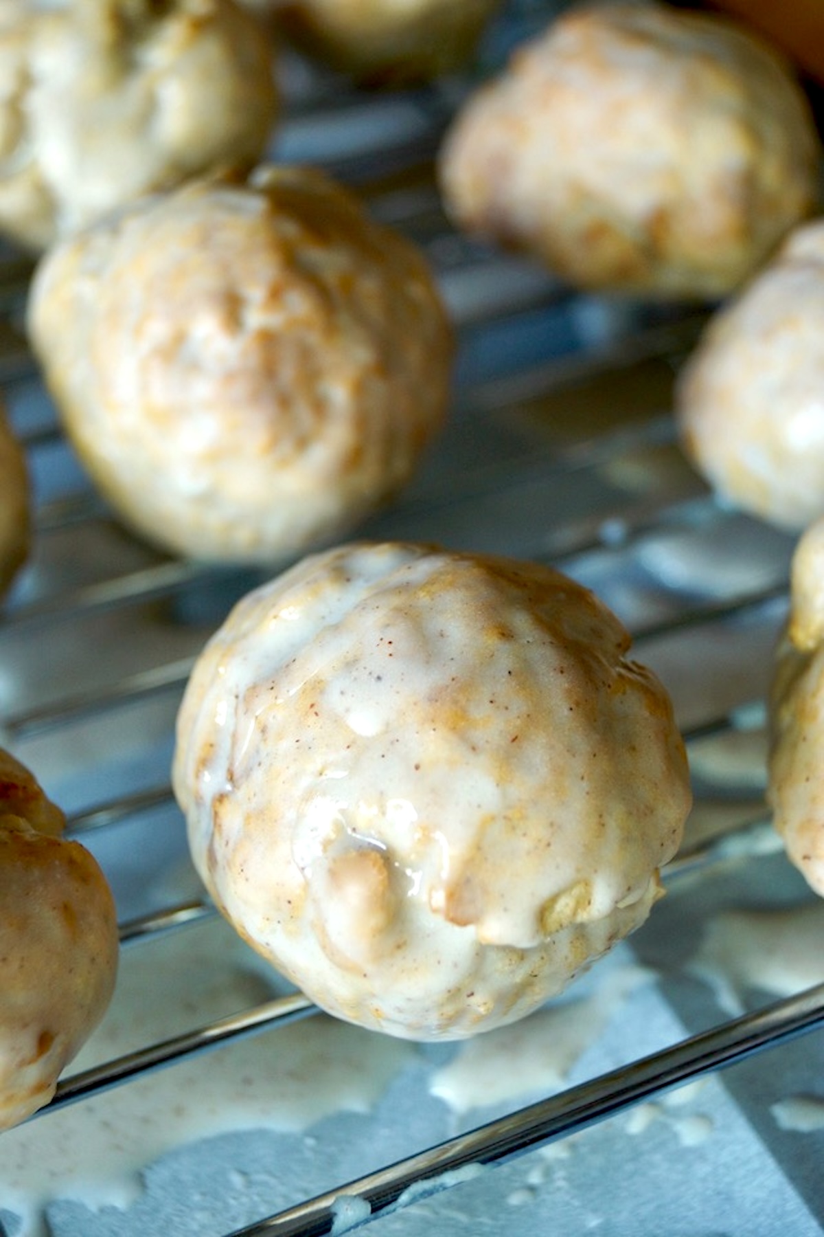 Baked and glazed donut holes on a baking rack.
