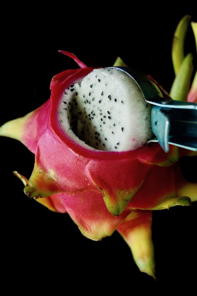 Dragon fruit being scoope out of skin with an ice cream scooper