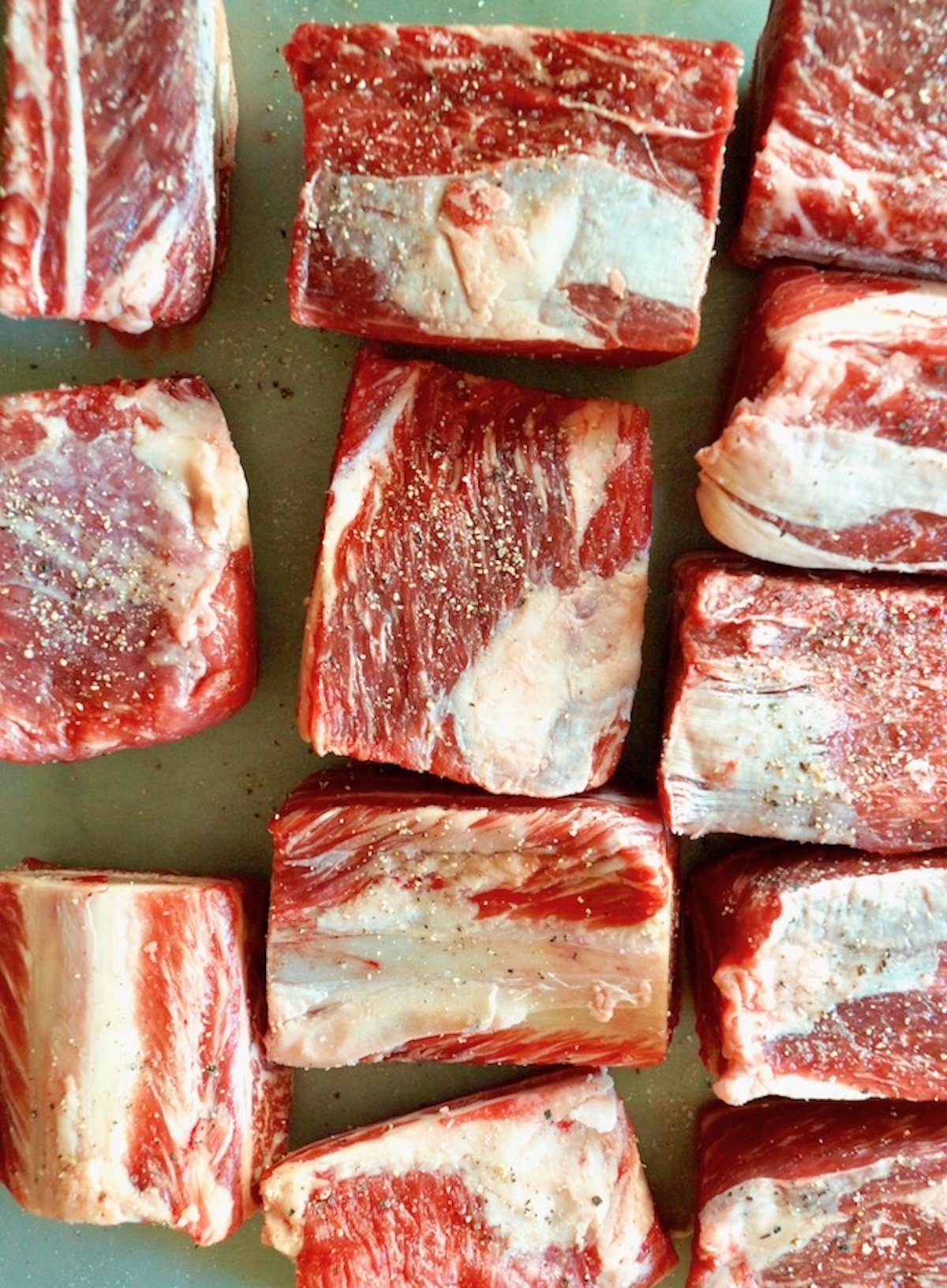 Several raw short ribs with salt and pepper.