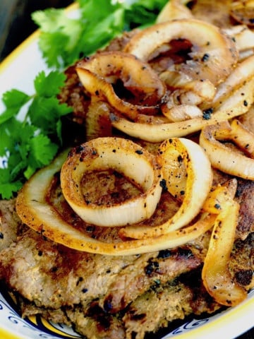 Steak with lots of golden onions on top.