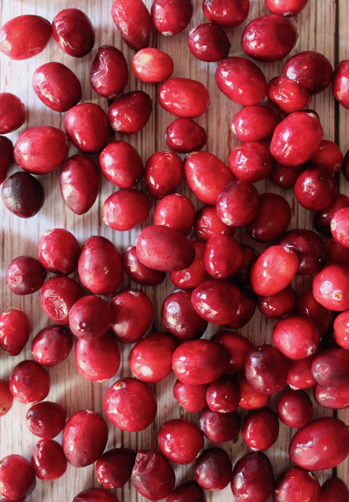 fresh raw cranberries spilled out on white wood