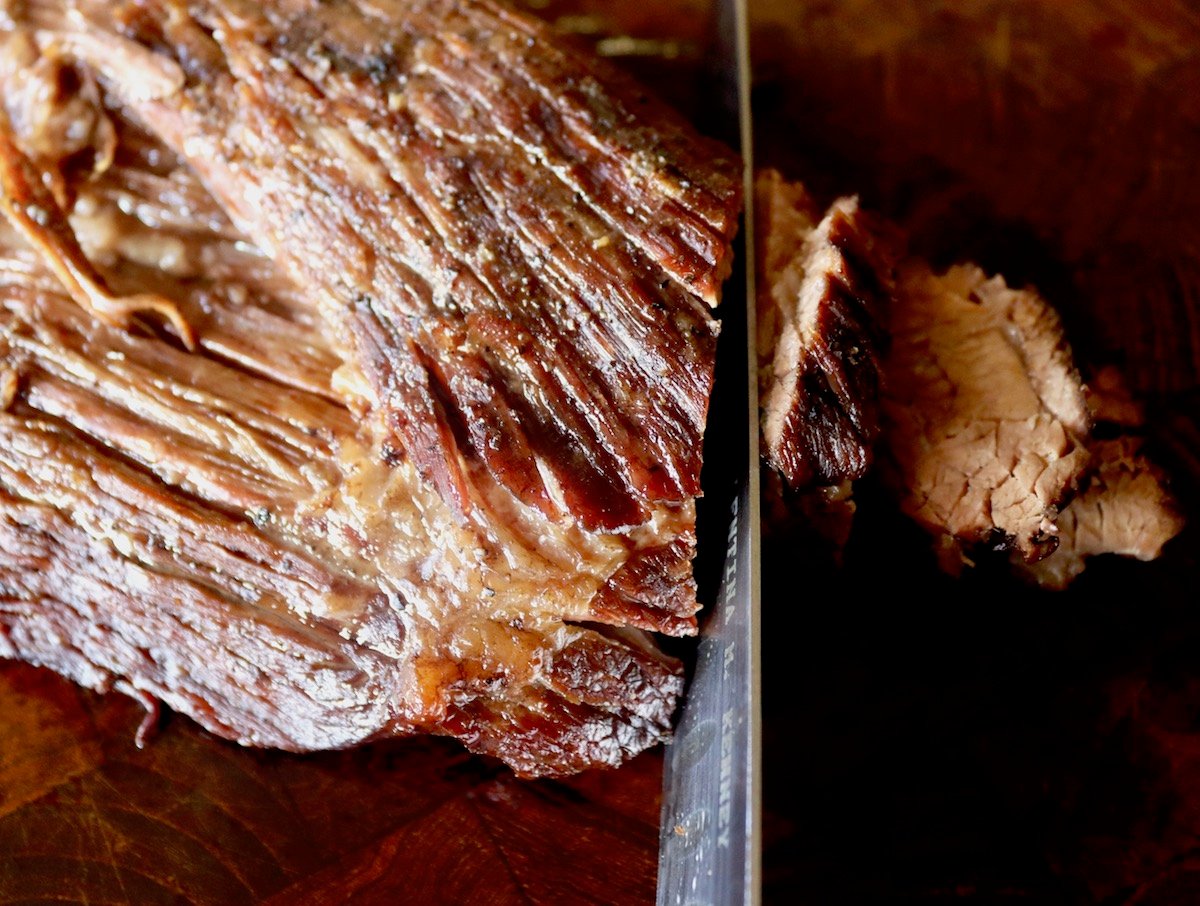 Cooked brisket being sliced against the grain.