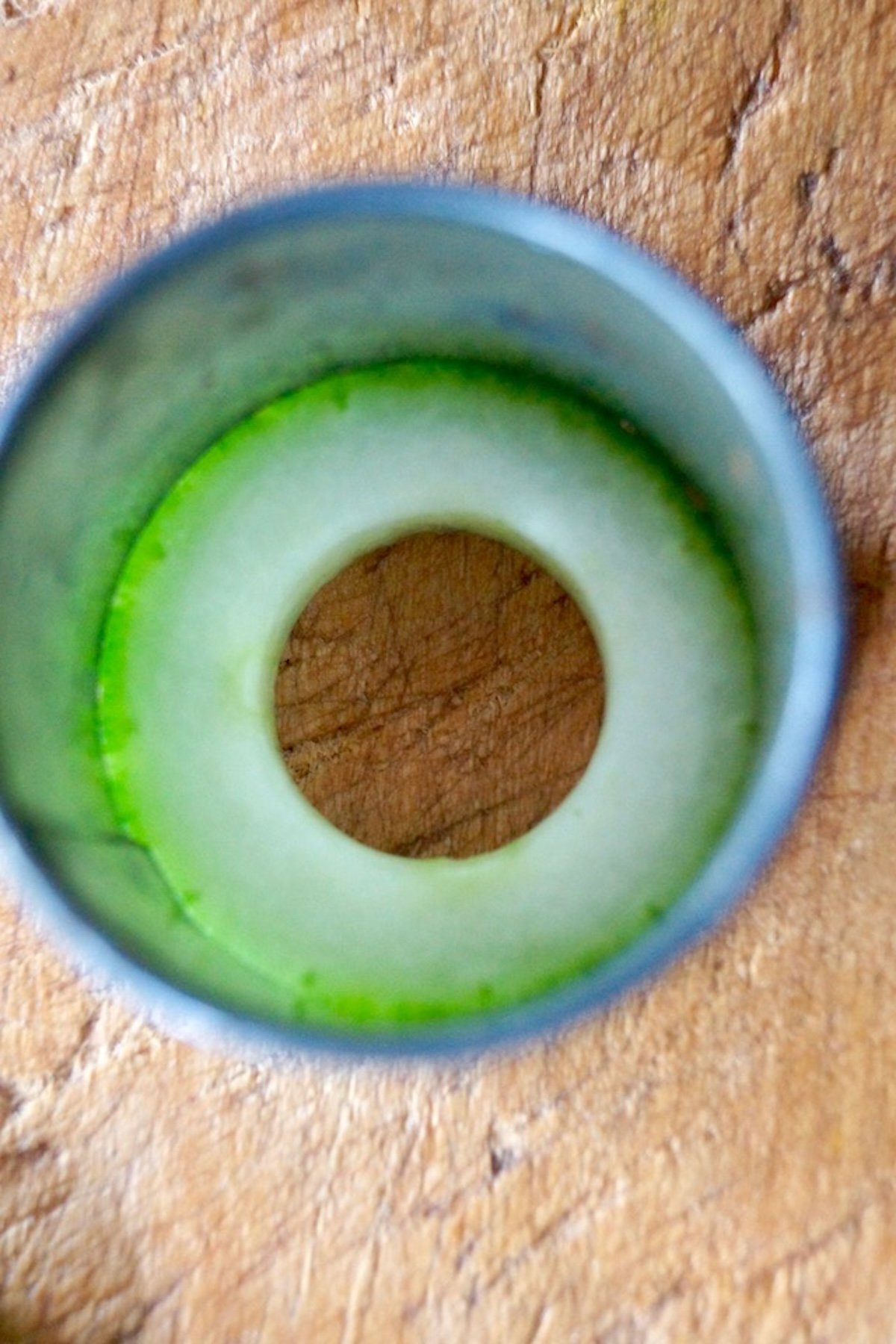 op view of a round cutter around a cucumber slice, to cut off the skin.