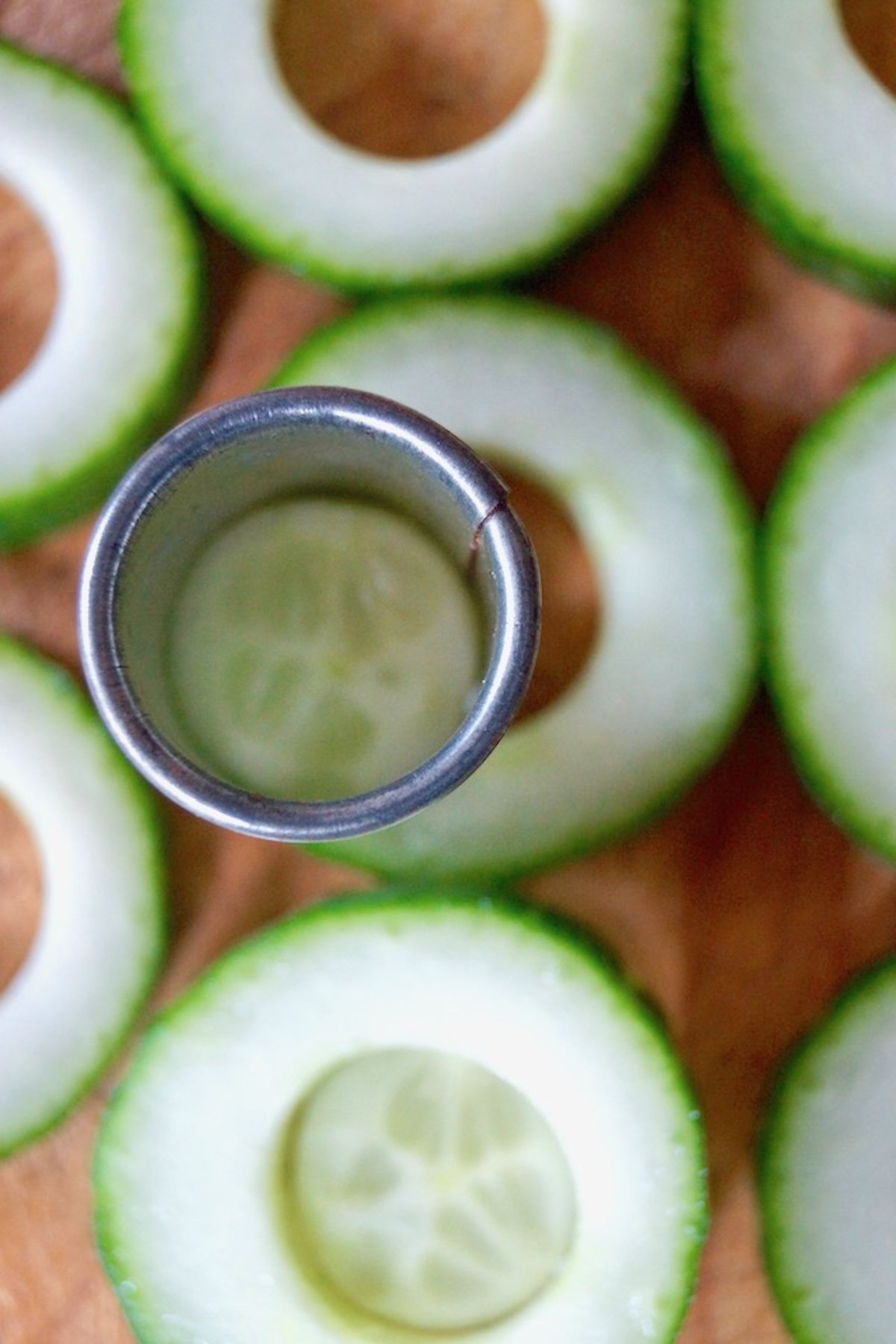 Cucumber slices with a round cutter cutting out he centers of each slice.