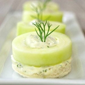 row of several cucumber dill canapes on white plate