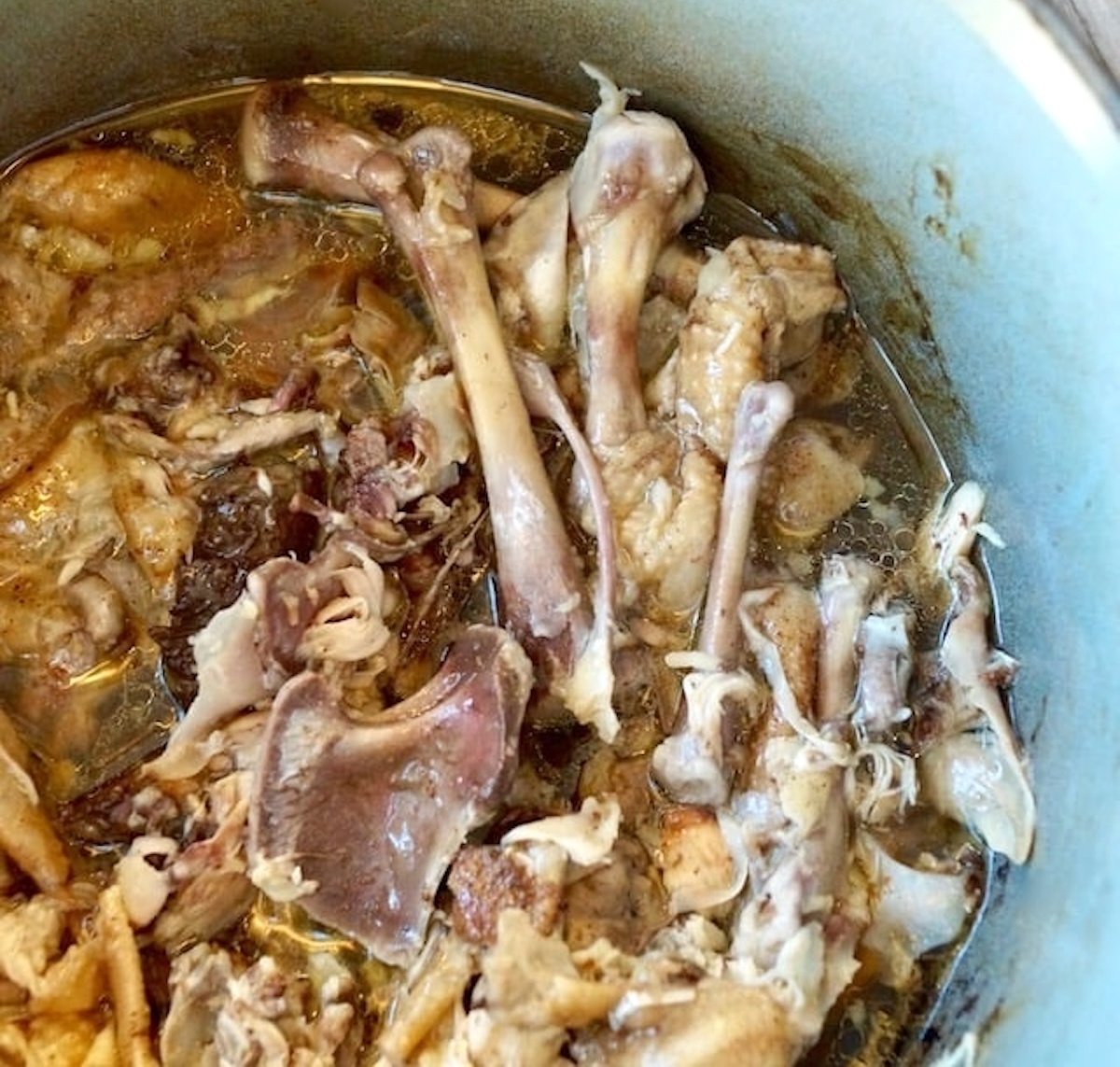 Chicken bones in a pot with chicken stock.