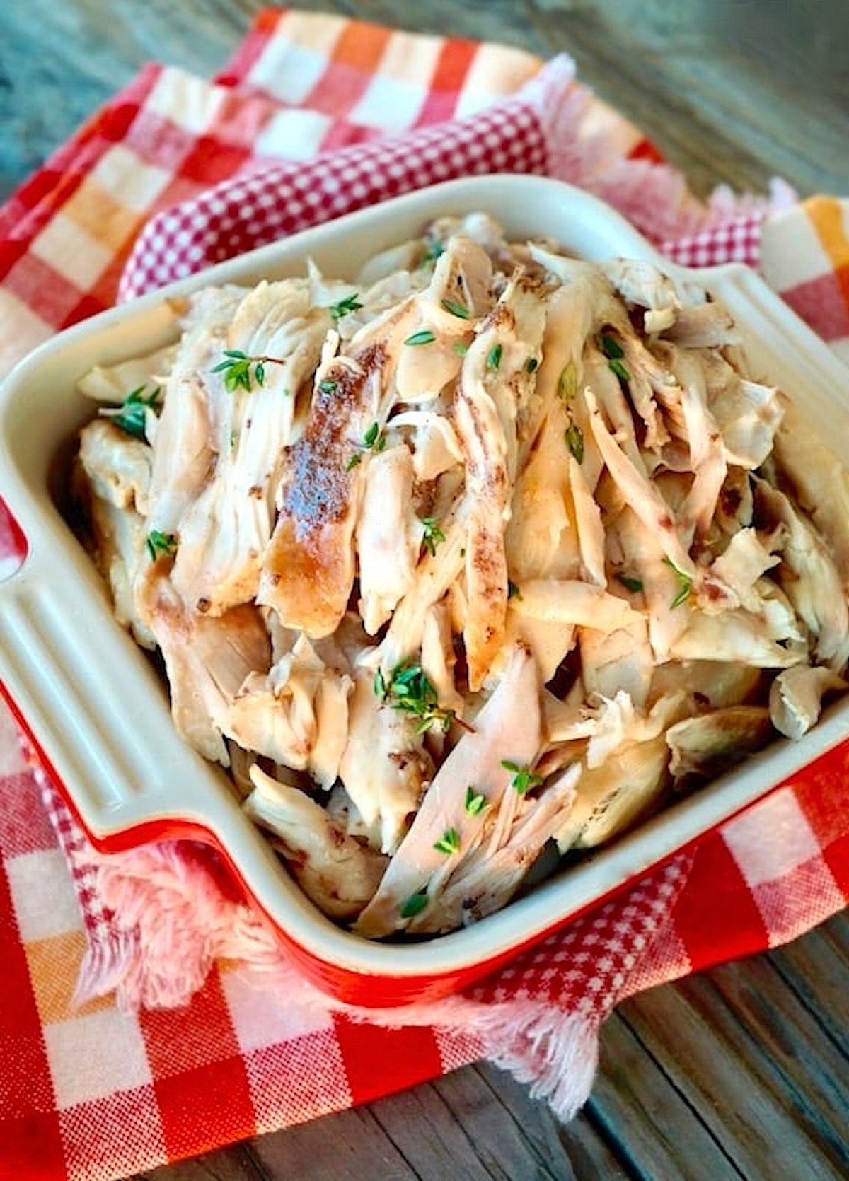 Shredded Fall-Apart Dutch-Oven Chicken in a small square casserole dish on a red-checked cloth.