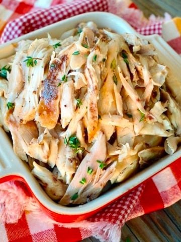 Shredded Fall-Apart Dutch-Oven Chicken in a small square casserole dish on a red-checked cloth.