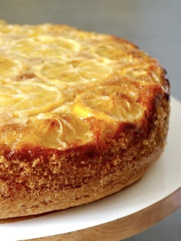 Whole Lemon Olive Oil Cake on white wood cake stand.