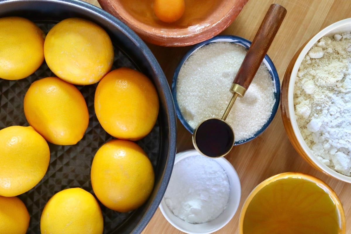 Ingredients for lemon olive oil cake including lemons, vanilla extract baking soda, baking powder, salt, olive oil. sugar, eggs, almond flour and gluten-free flour.