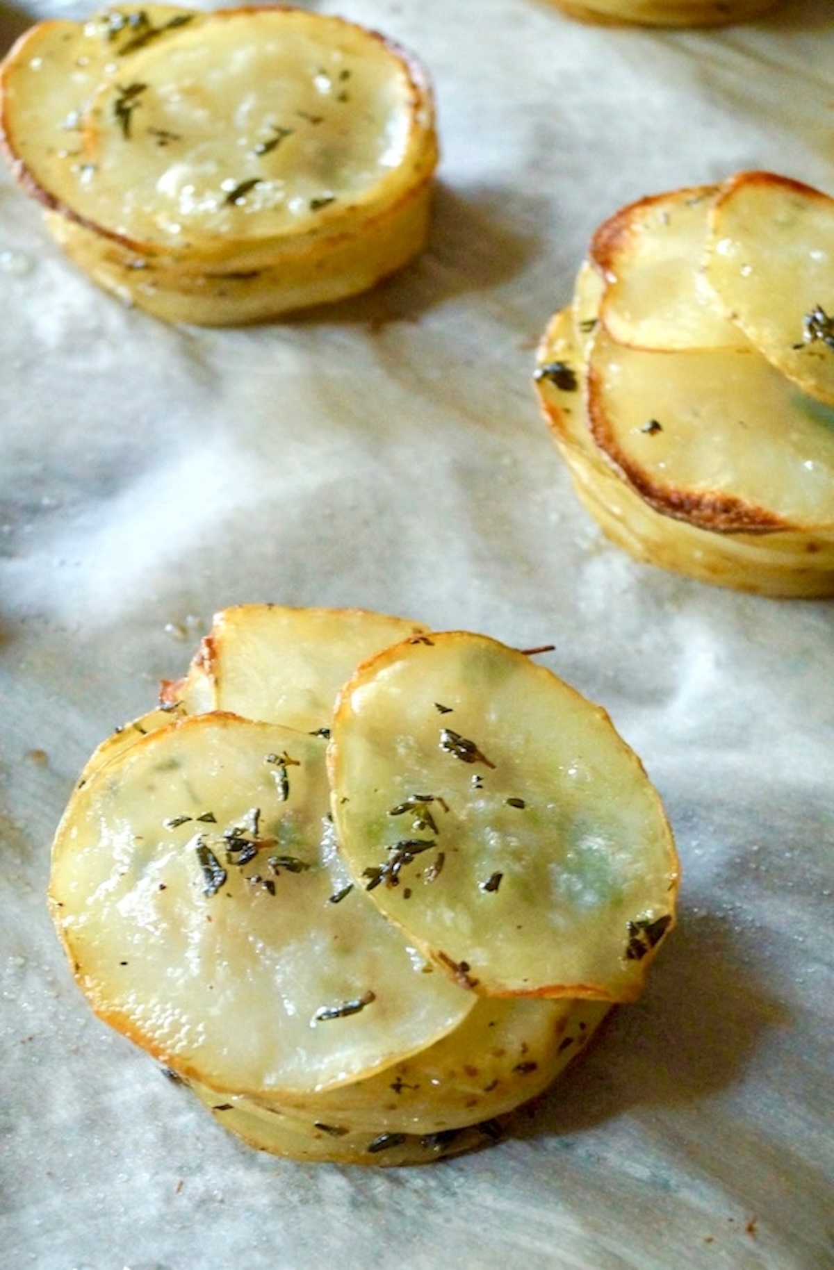 A few individual Pommes Anna potato stacks on parchment paper.