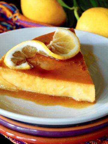One slice of meyer lemon flan on a white plate with a twisted lemon slice.