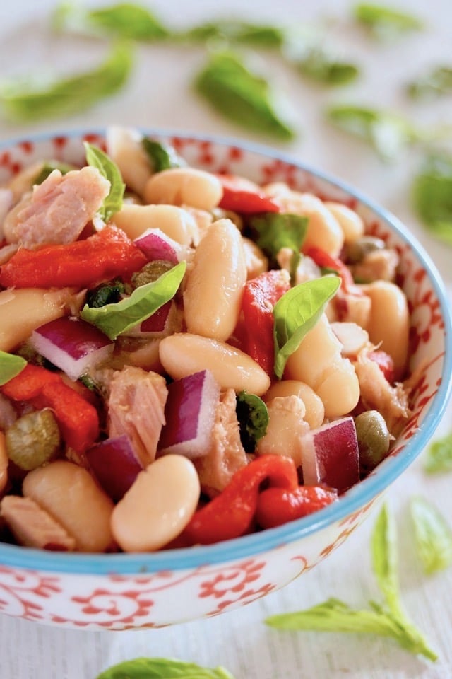 Cannelllini Bean Tuan Salad i a white bowl with blue trim and red flowers on it.