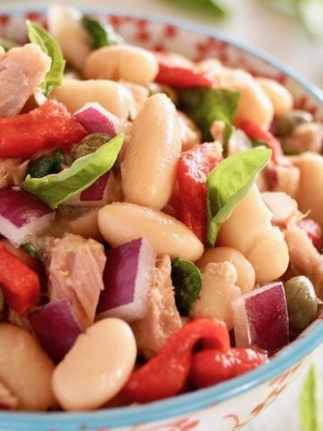 Cannelllini Bean Tuan Salad i a white bowl with blue trim and red flowers on it.