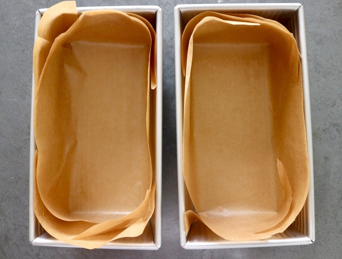 Two loaf pans lined with parchment paper. 