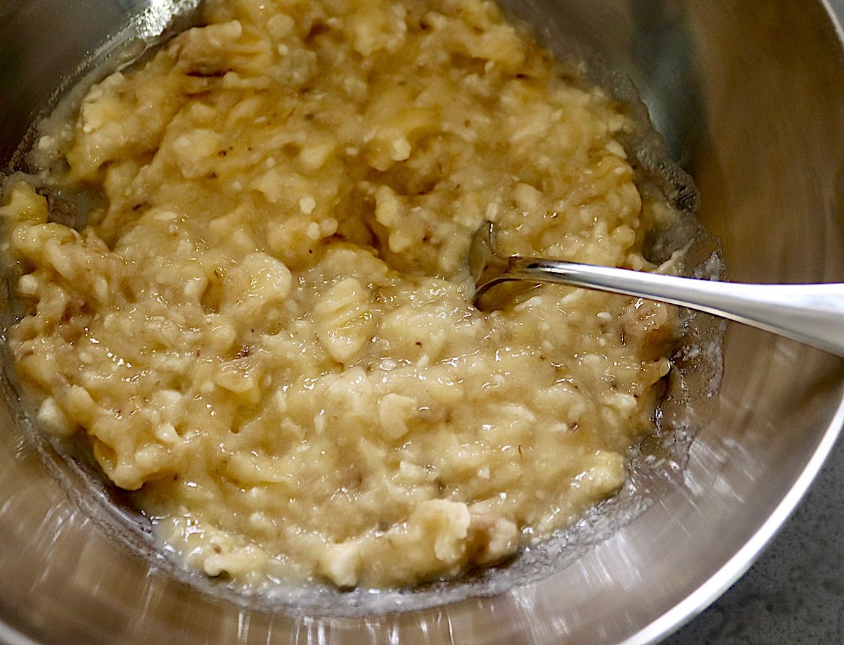 Mashed banana in stainless steel bowl with a fork.