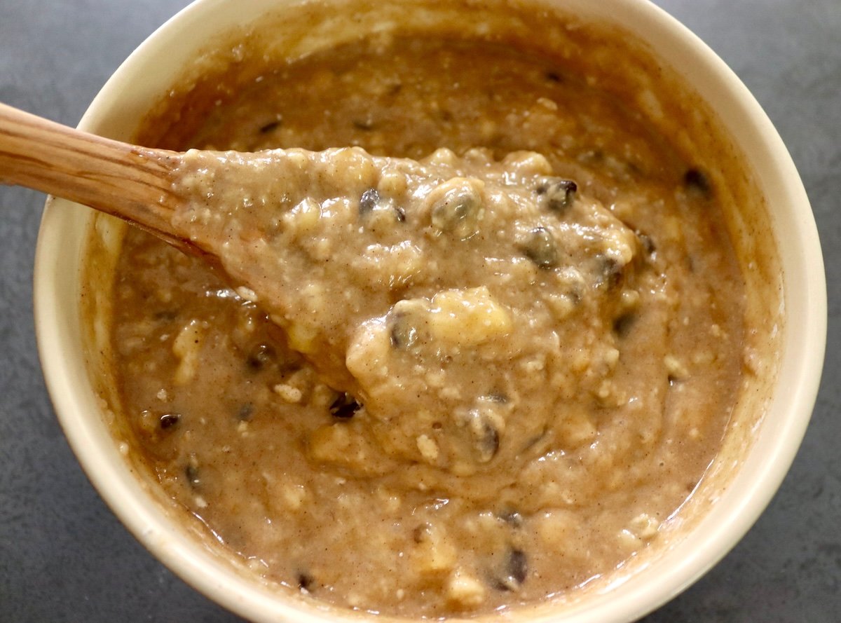Bowl filled with chocolate chip banana cake batter and a wooden spoon.
