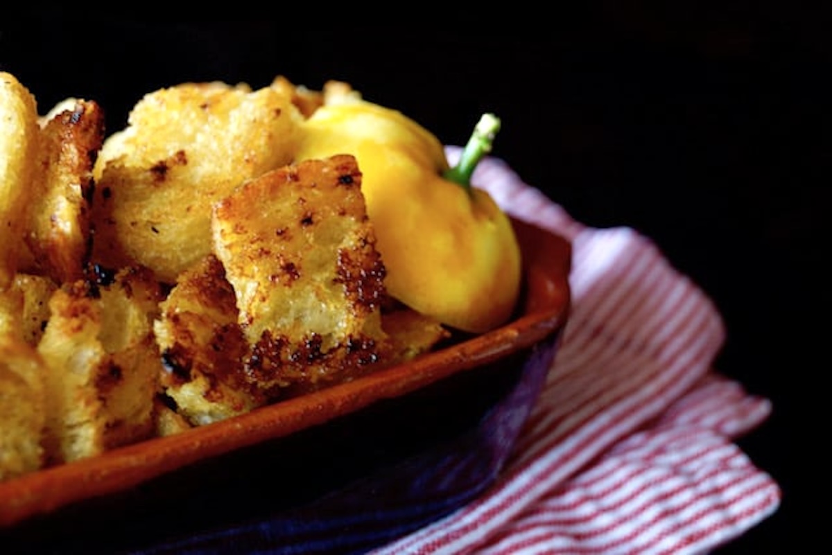 Fried-Lemon-Caesar-salad-Recipe Small ceramic casserole dish full of garlic lemon croutons and part of a lemon with stem.