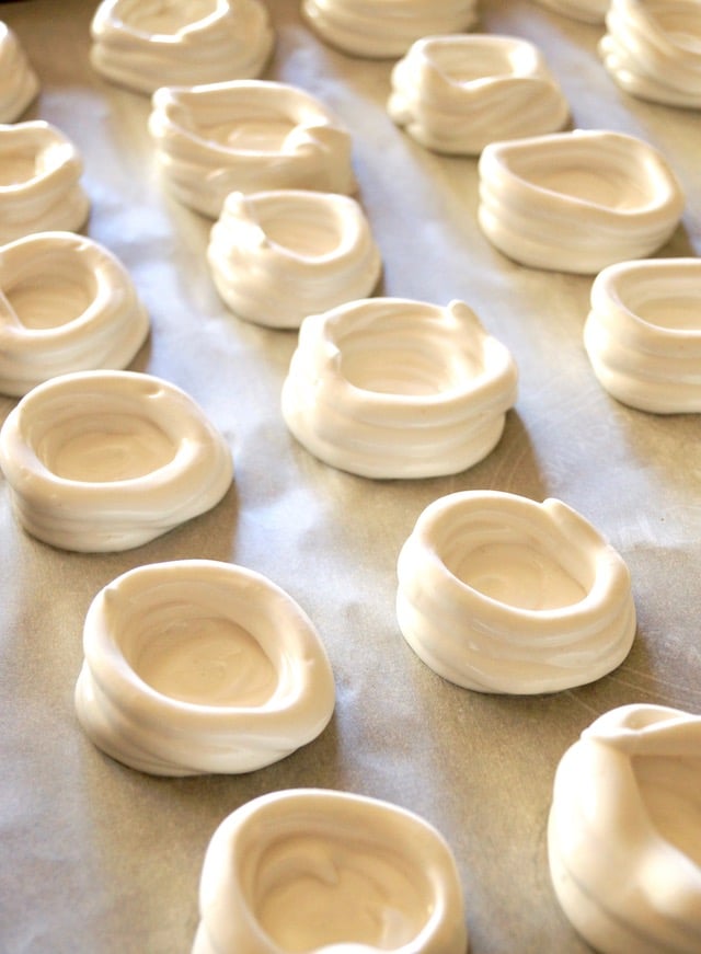 Meringue freshly piped into bowls for mini pavlova nests.