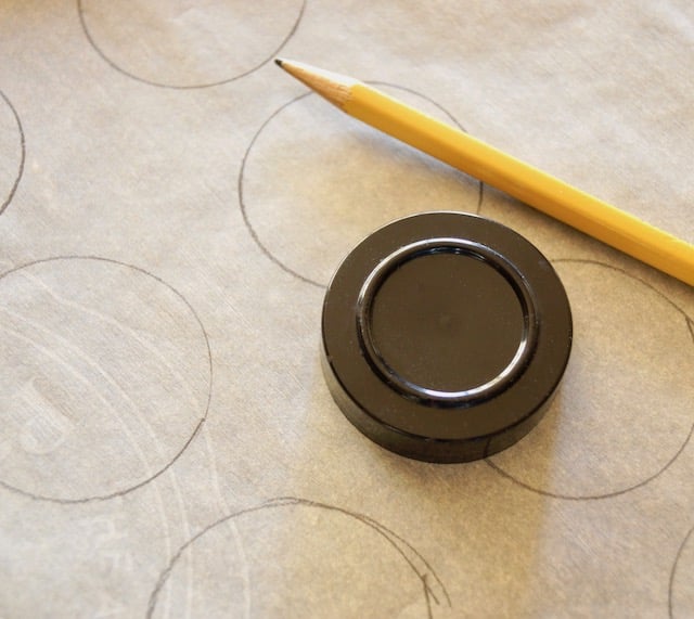 parchment paper with pencil and small black lid to trace for meringue bases for Pavlova