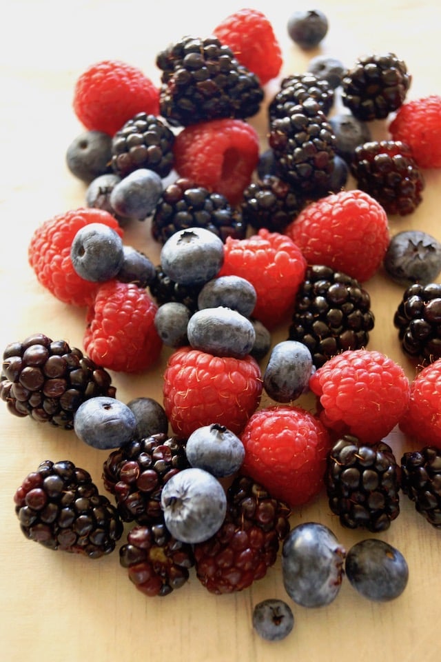 Pile of fresh blueberries, blackberries and respberries on white background