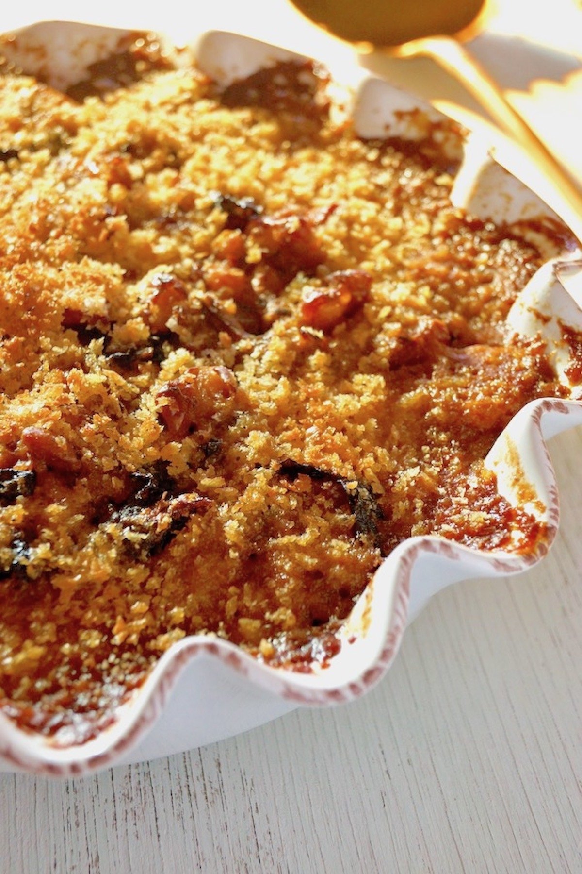 Vegetarian Cassoulet in a white pie dish with a gold spoon next to it.