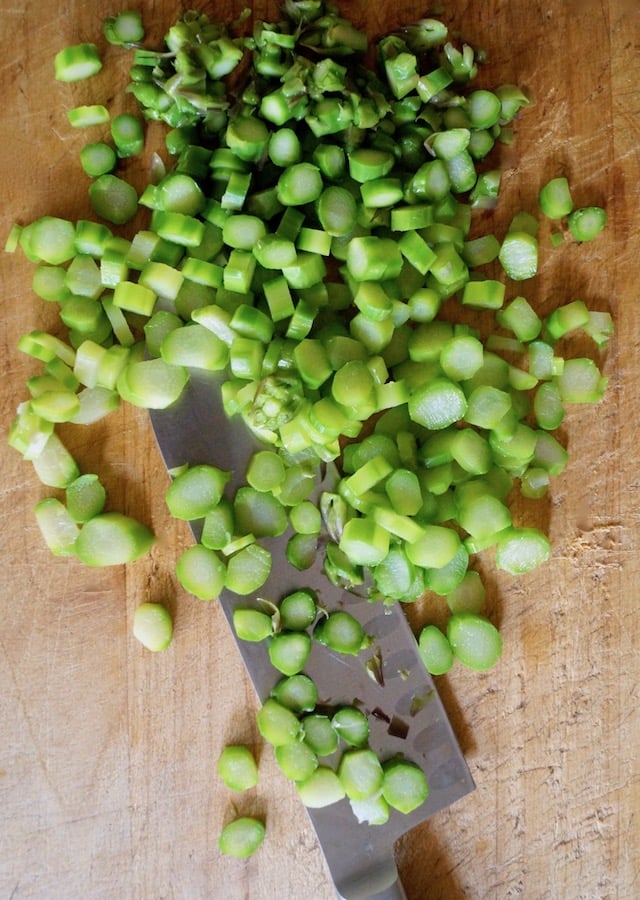 Finely chopped, steamed asparagus on a cutting board with knife