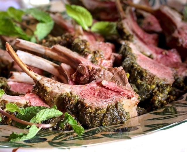 Several Pistachio Mint Cursted Lamb Chops on a platter with fresh mint