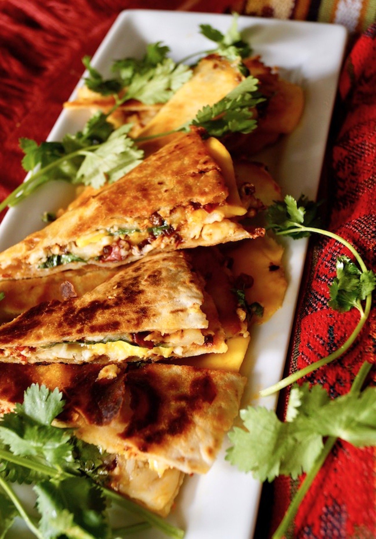 Long white rectangular plate with several slices of mango quesadilla.