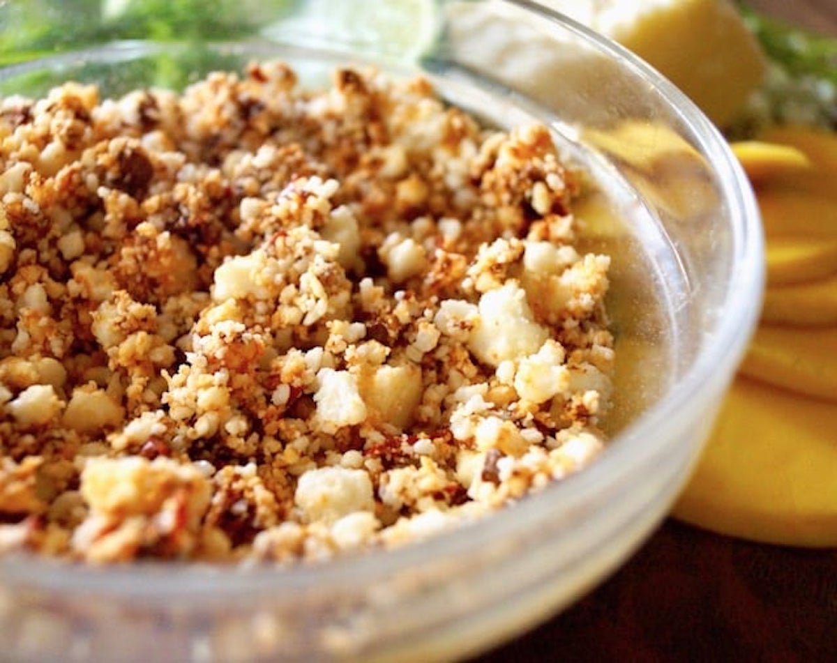 Glass bowl with crumbled Cotiaja cheese mixed with red adobo sauce.